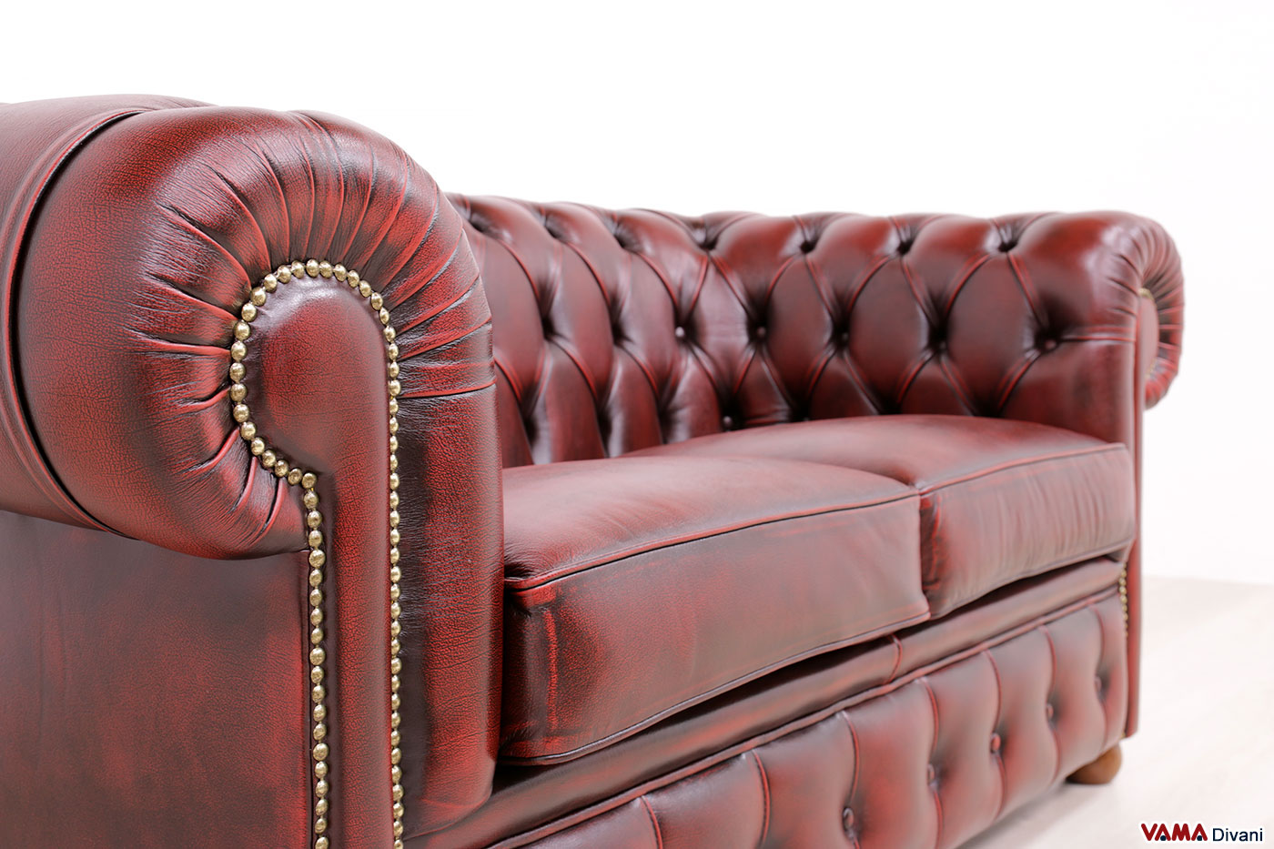 Détail cloutage laiton sur accoudoir Chesterfield rouge